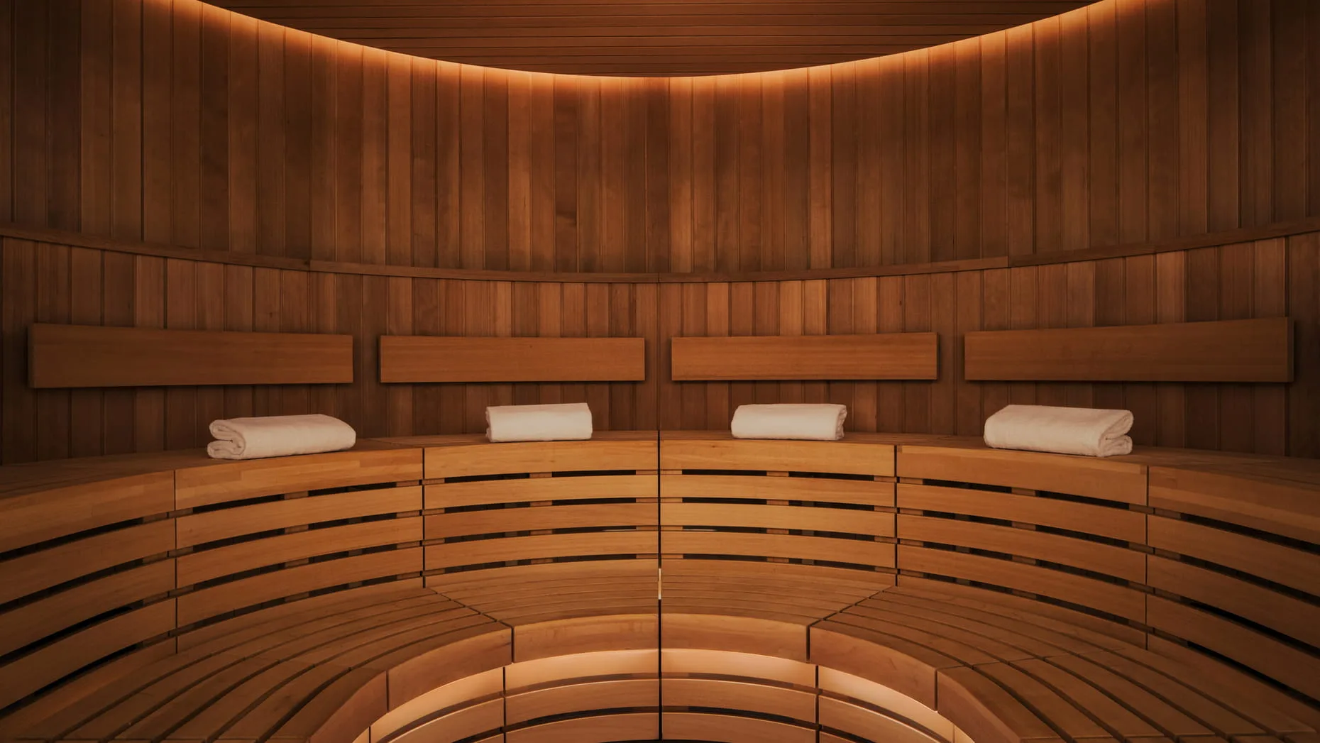 Round wood-paneled sauna with tiered benches, four rolled white towels, and amber light at Naples Beach Club, A Four Seasons Resort, Florida