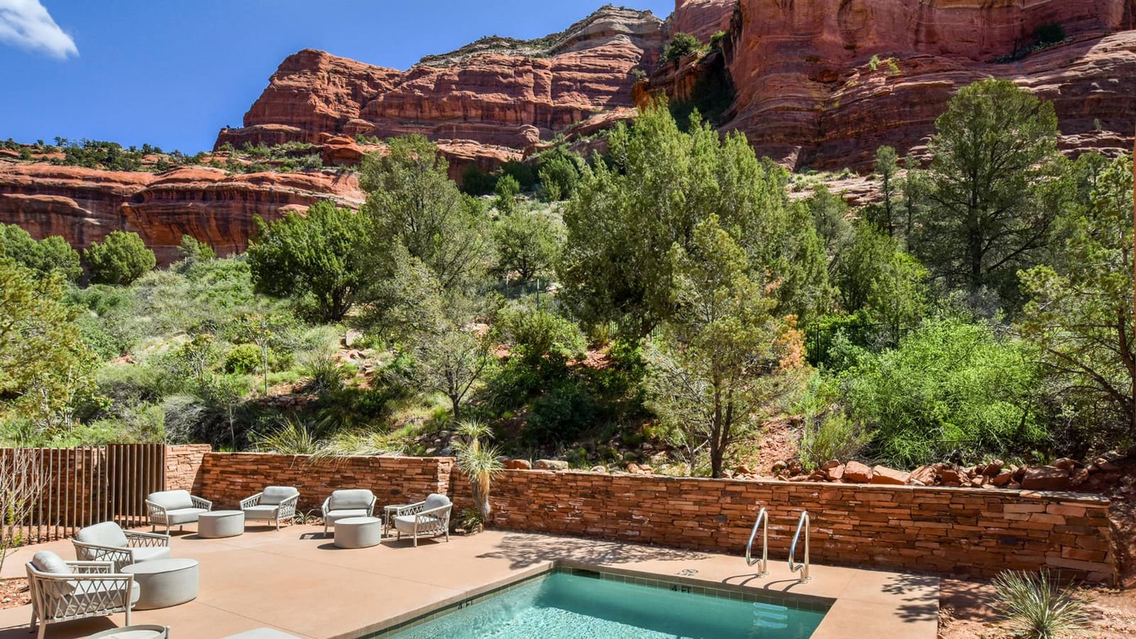 A small square pool with turquoise water and grey loungers at Mii amo in Sedona, set against red rock cliffs.