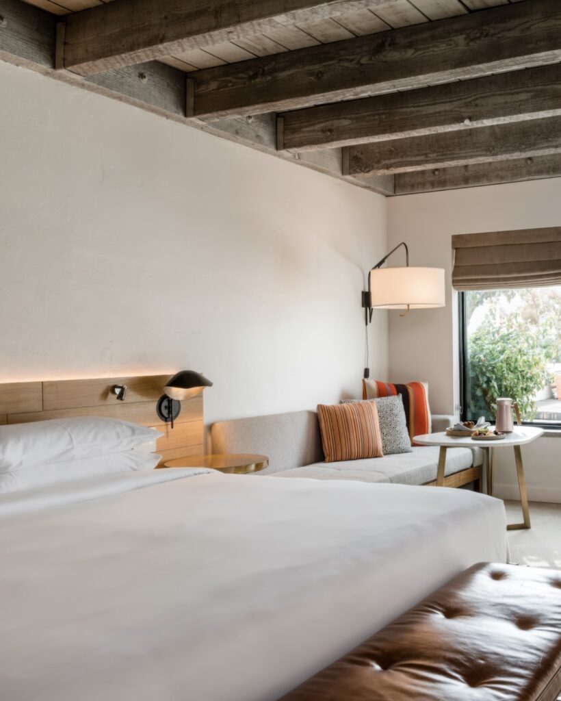 Bungalow guest room with exposed timber beam ceiling, striped cushions, and leather bench at Andaz Scottsdale Resort & Bungalows