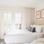 Bright white guest room with linen headboard, blue accent pillow and French doors to balcony at Arizona Grand Resort & Spa, Phoenix