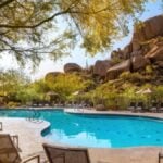 Freeform pool with loungers and parasols set against towering granite boulders and palo verde trees at Boulders Resort & Spa Scottsdale, Scottsdale