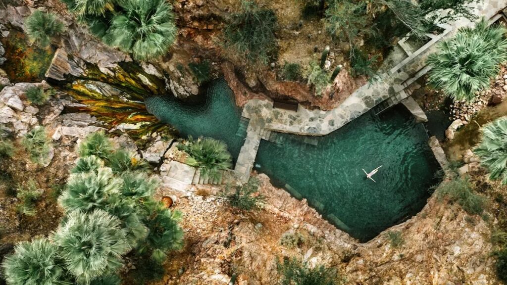 Aerial view of natural hot spring pools in a rocky canyon with mineral-green water at Castle Hot Springs, Morristown