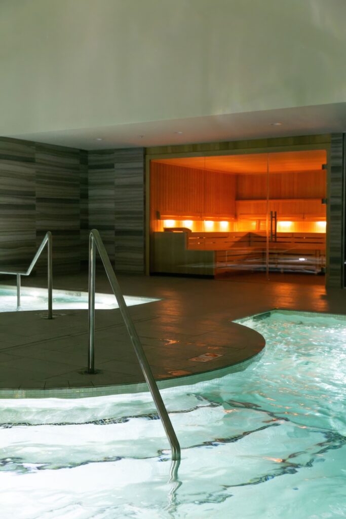 Indoor hydrotherapy plunge pool with grey stone walls and cedar sauna visible beyond at CIVANA Wellness Resort and Spa, Carefree