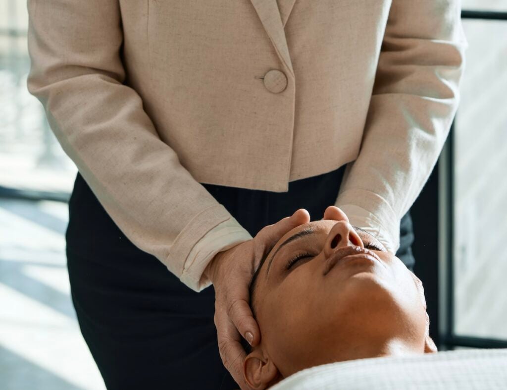 Therapist performing cranial massage with both hands cradling client's head at The Global Ambassador, Phoenix