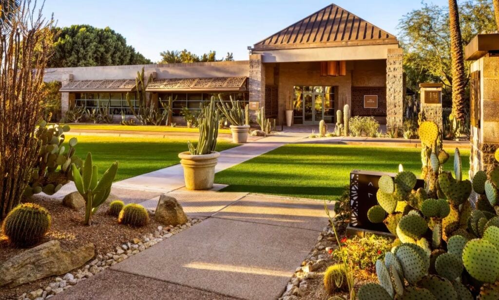 Spa entrance pathway through a cactus garden with stone and timber porte-cochère at golden hour at Grand Hyatt Scottsdale Resort