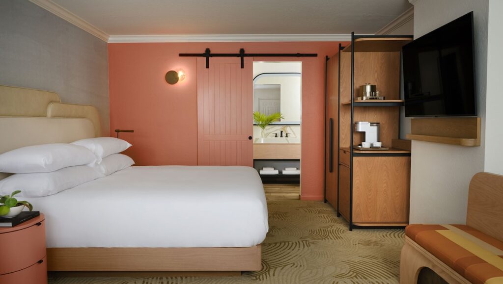 King guest room with coral accent wall and sliding barn door to bathroom at Kimpton Miralina, Scottsdale