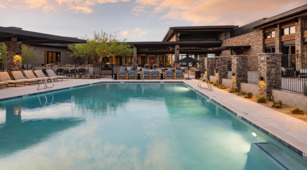 Heated outdoor pool surrounded by loungers and stone-clad buildings at dusk at Mountain House Lodge at Sereno Canyon, Scottsdale