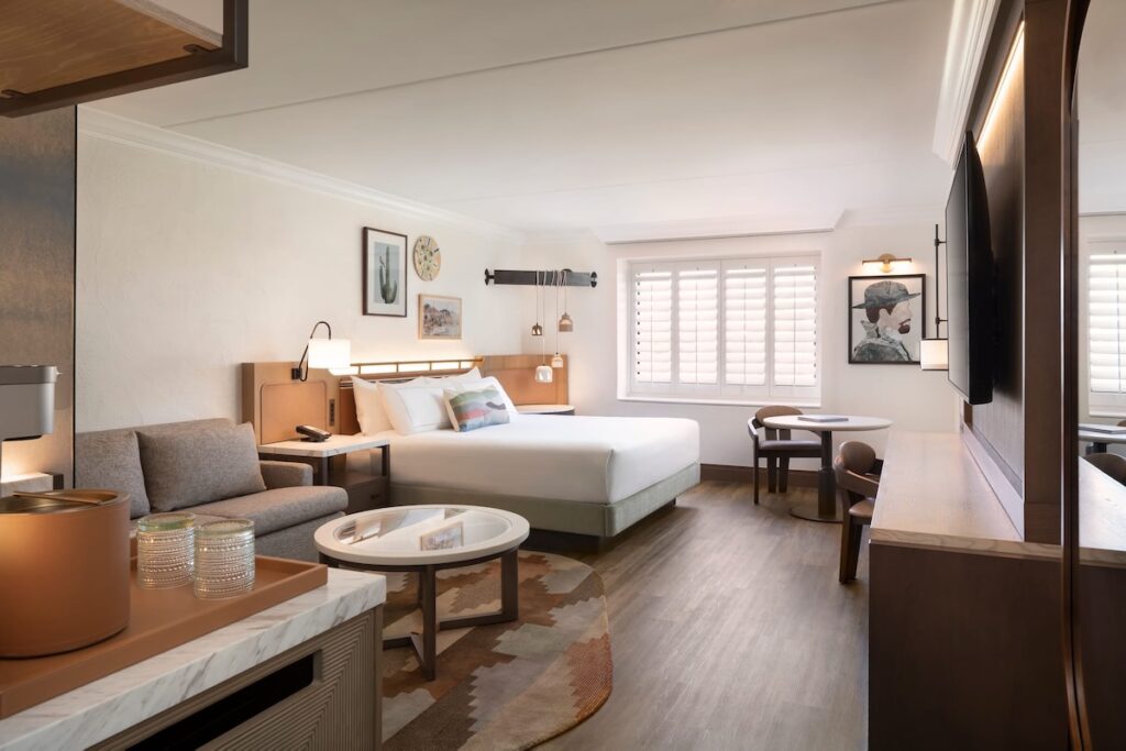 Renovated king guest room with desert-inspired artwork and marble accent furniture at The Scottsdale Resort and Spa