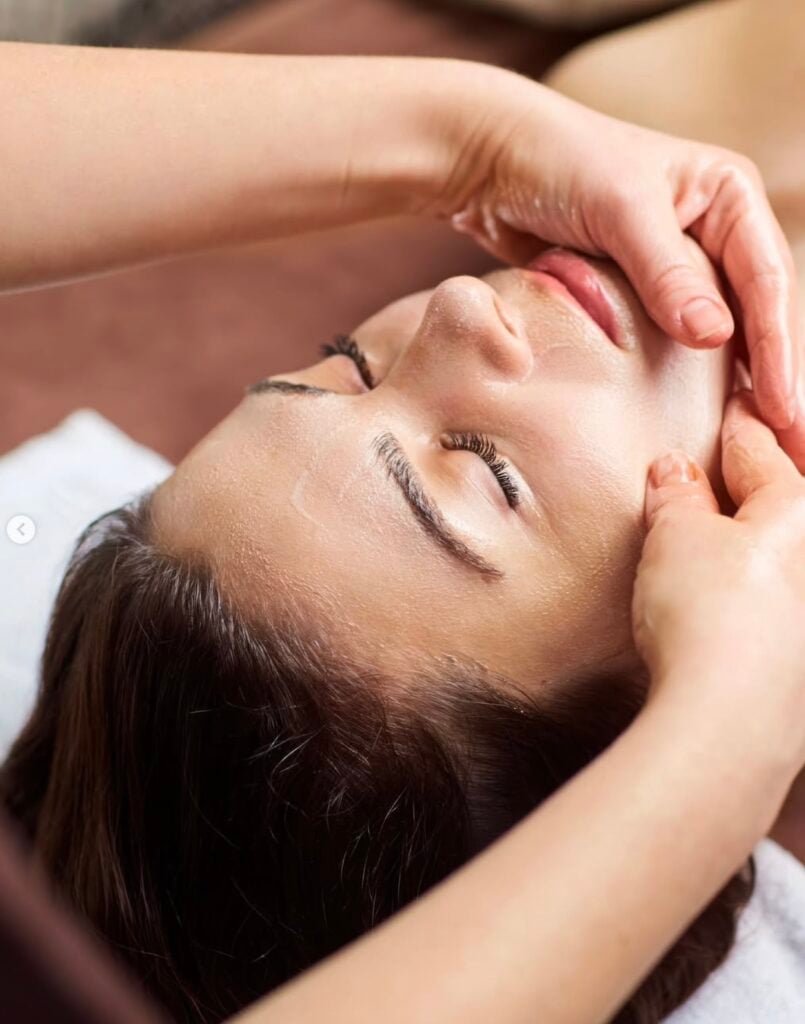Therapist performing facial massage on woman with closed eyes on white treatment table at Hilton Phoenix Tapatio Cliffs Resort, Phoenix