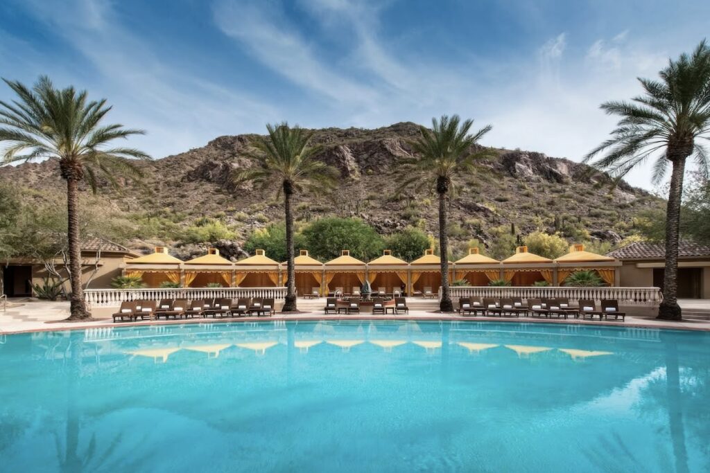 Main pool with gold-canopied cabanas and date palms beneath Camelback Mountain at The Phoenician, Scottsdale