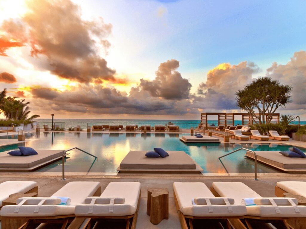 Rooftop pool terrace at sunset with in-water teak platforms and ocean horizon at 1 Hotel South Beach, Miami Beach