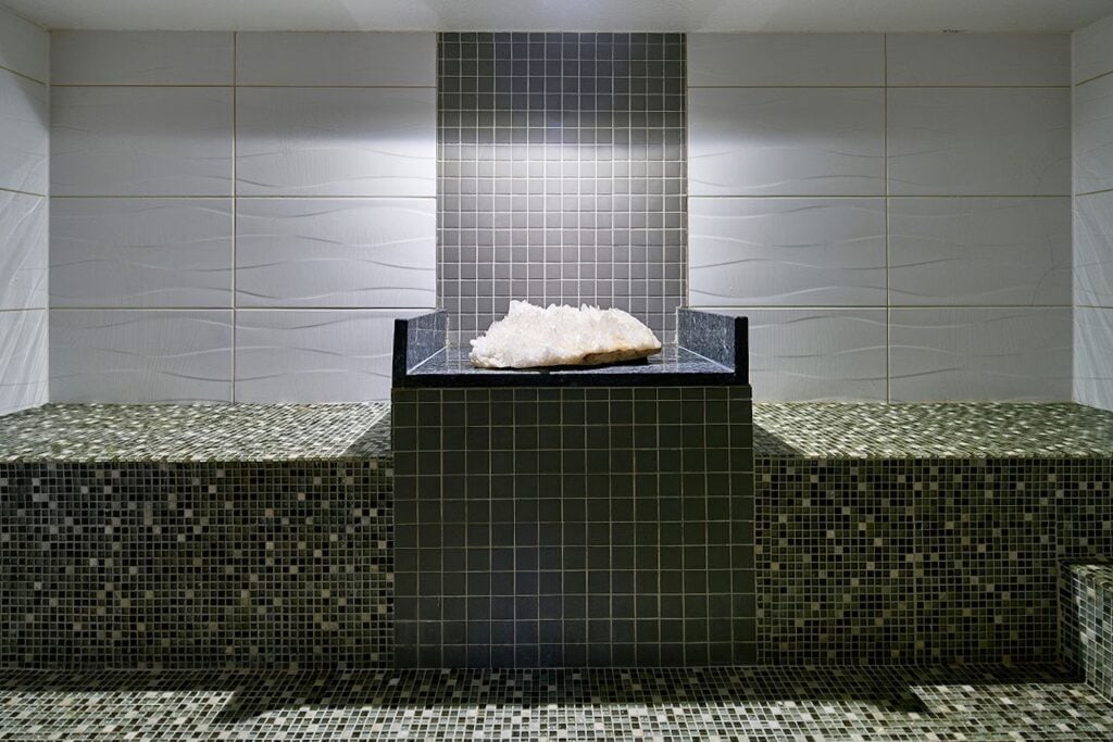Steam room with quartz crystal centrepiece and dark mosaic tile benches at Carillon Miami Wellness Resort, Miami Beach