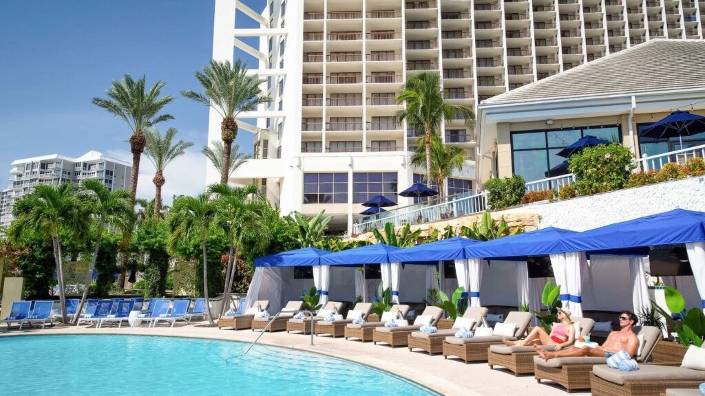 Outdoor pool with blue cabanas and wicker sun loungers at Naples Grande Beach Resort, Naples Florida