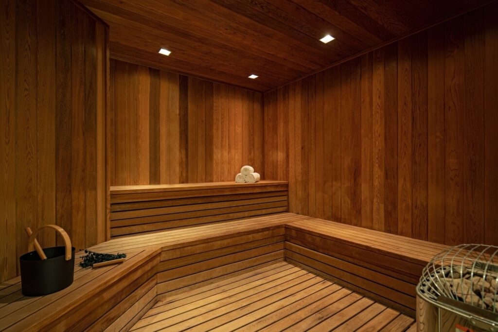 Cedar-lined dry sauna with tiered benches, rolled towels and Harvia stone heater, The St. Regis Bal Harbour Resort