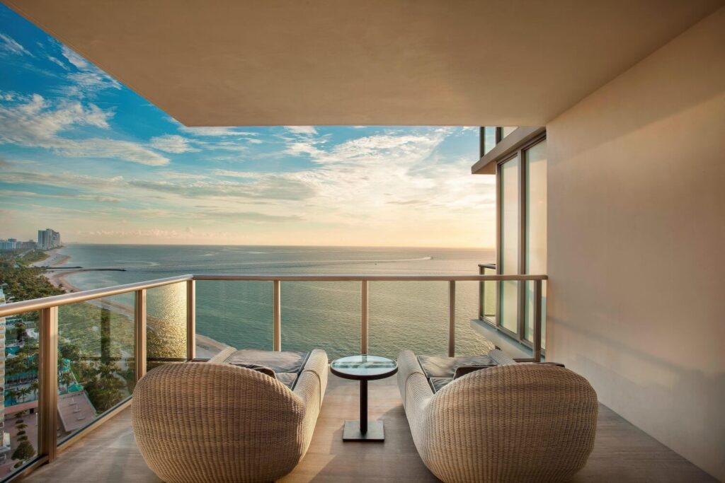 High-floor suite balcony with wicker lounge chairs overlooking the Atlantic at sunset, The St. Regis Bal Harbour Resort