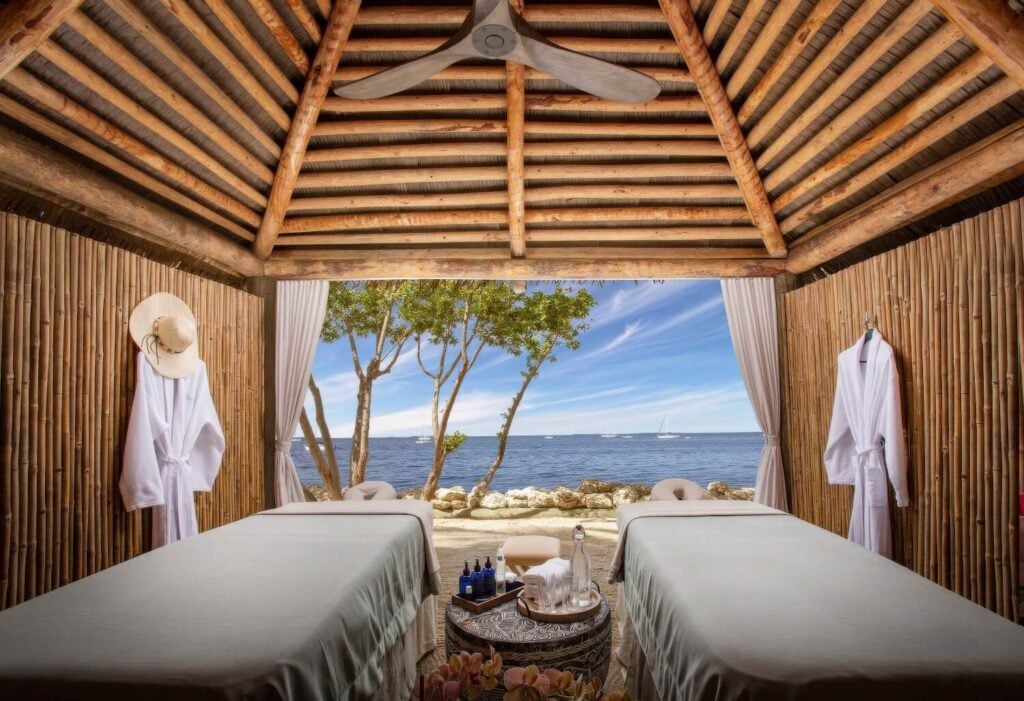 Oceanfront massage cabana with twin tables, robes, and beach view at Bungalows Key Largo, Florida Keys