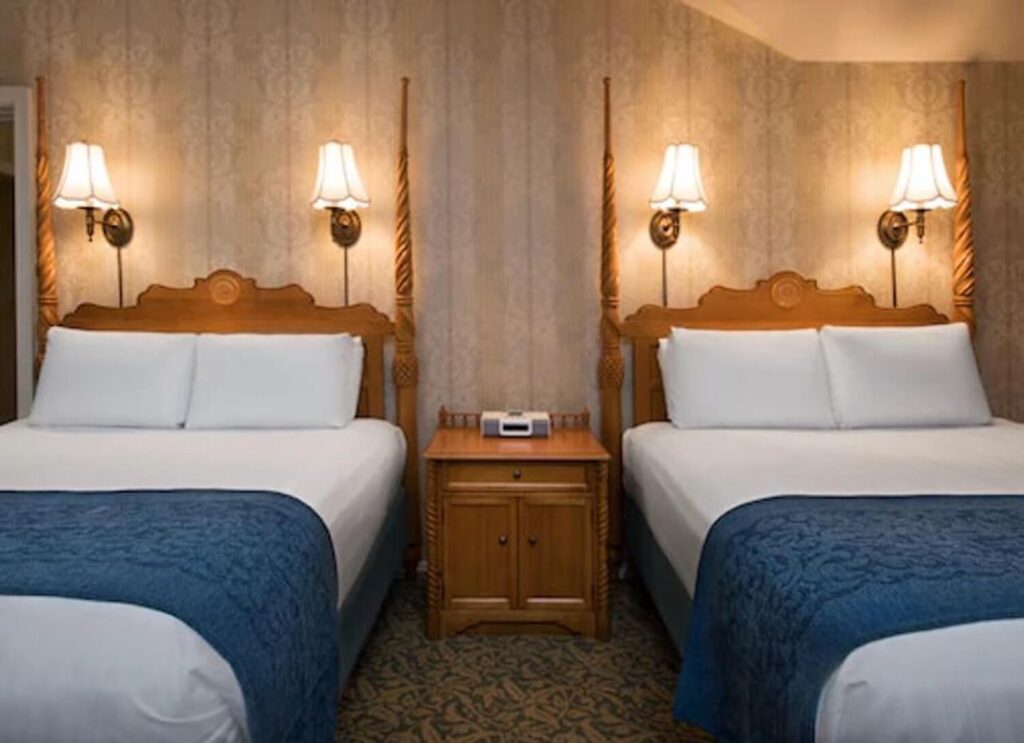 Classic guest room at Disney's Grand Floridian Resort & Spa, Orlando, with two beds, carved headboards and blue quilted covers.