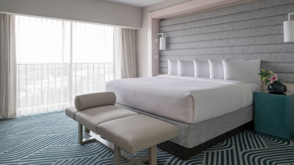 King guest room at Hyatt Regency Grand Cypress, Orlando, with an upholstered headboard, bench seat and patterned teal carpet.