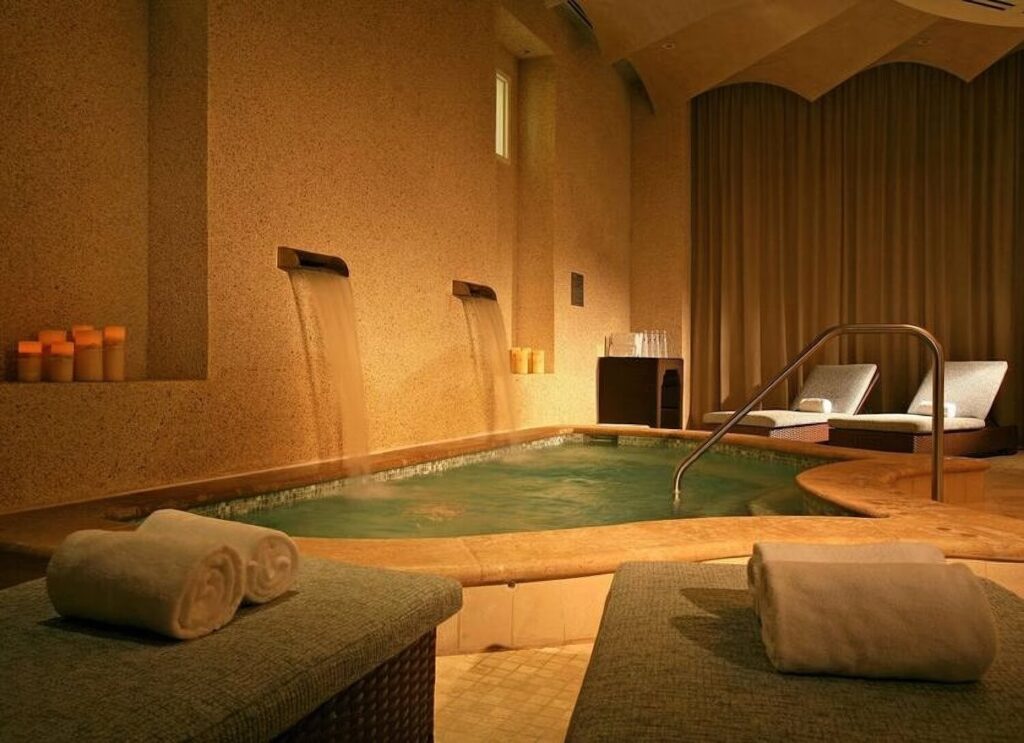 Candlelit spa hydrotherapy pool with cascading water spouts and loungers at Sandpearl Resort, Clearwater Beach, Florida