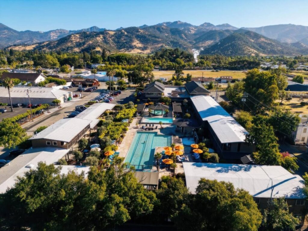 Aerial view of the resort's four mineral pools, orange umbrellas and buildings ringed by mountains at Calistoga Spa Hot Springs, Calistoga
