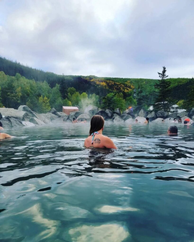 Bathers soaking in the rock-lined natural hot lake ringed by spruce forest at Chena Hot Springs, Alaska