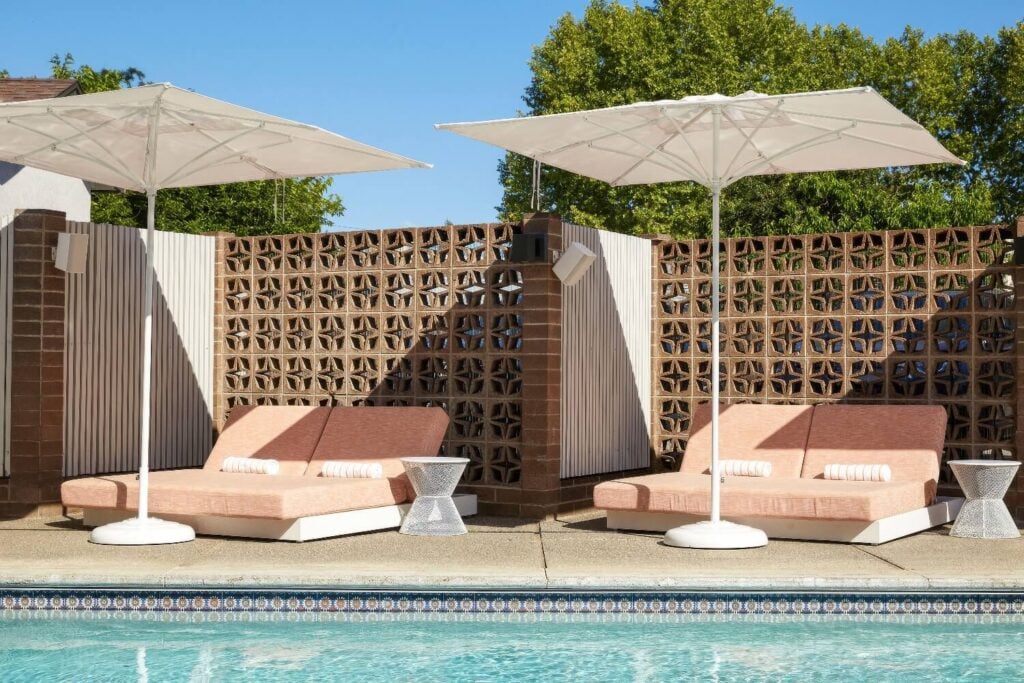 Pink double loungers under white umbrellas beside a mineral pool and breeze-block wall, Dr. Wilkinson's Backyard Resort, Calistoga