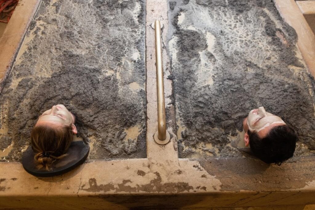 Overhead view of a couple lying face-up in a shared volcanic mud bath at Golden Haven Hot Springs Spa & Resort, Calistoga