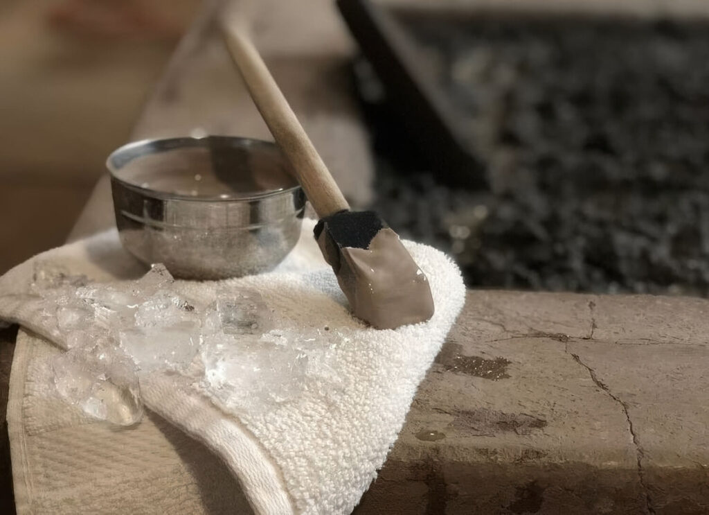 Close-up of a mud applicator, water bowl and ice cloth set on the edge of a volcanic mud bath at Golden Haven Hot Springs Spa & Resort, Calistoga