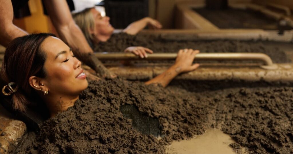 Two guests relaxing side by side in individual volcanic mud baths at Golden Haven Hot Springs Spa & Resort, Calistoga