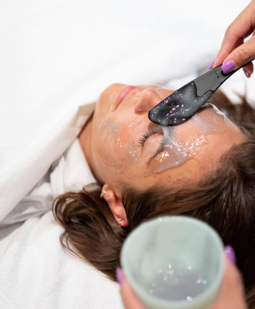 Esthetician applying a gel treatment mask to a guest's face during a facial at Harvest Inn, St. Helena