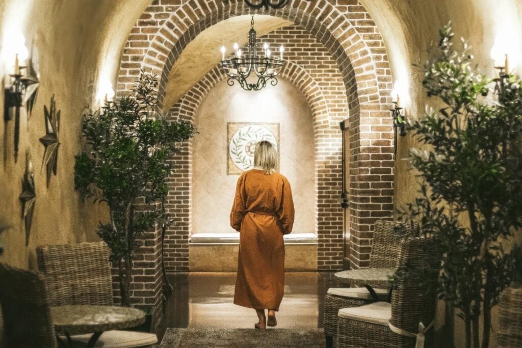 Guest in a robe walking through the brick-arched underground Spa Terra cave at The Meritage Resort and Spa, Napa