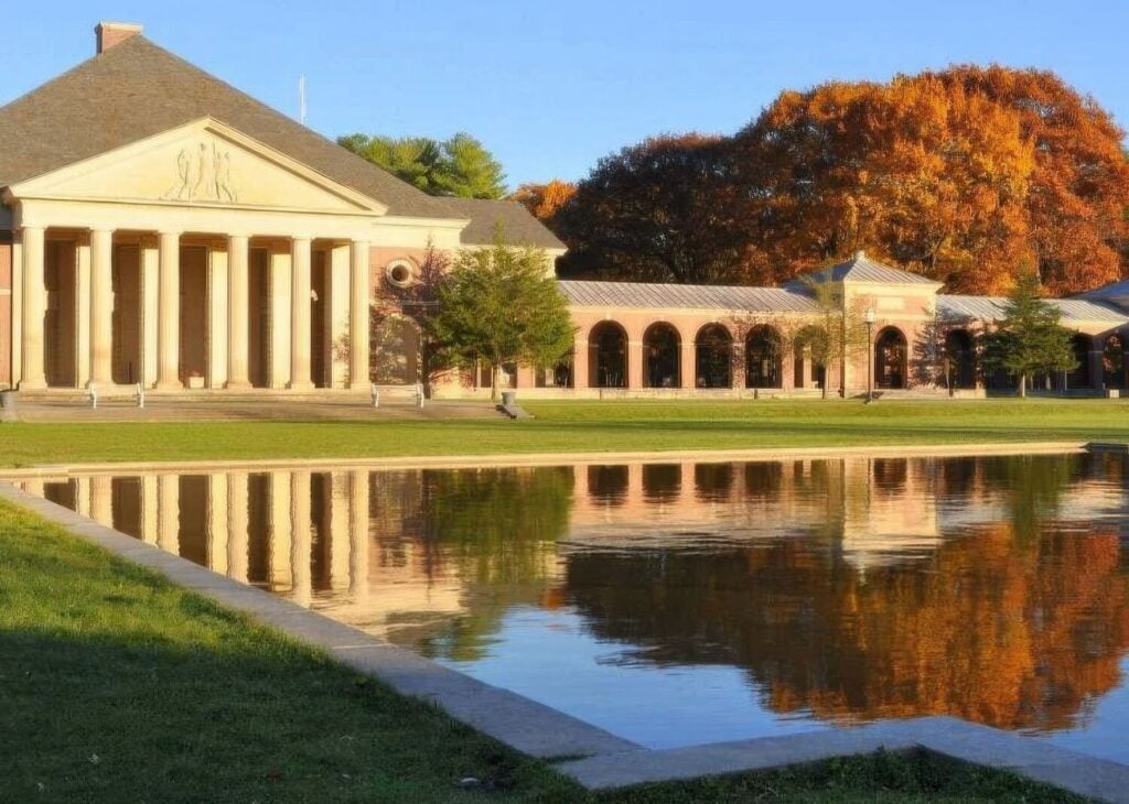 The neoclassical Hall of Springs and Roosevelt Baths colonnade reflected in a pool amid autumn colour at Saratoga Spa State Park, New York