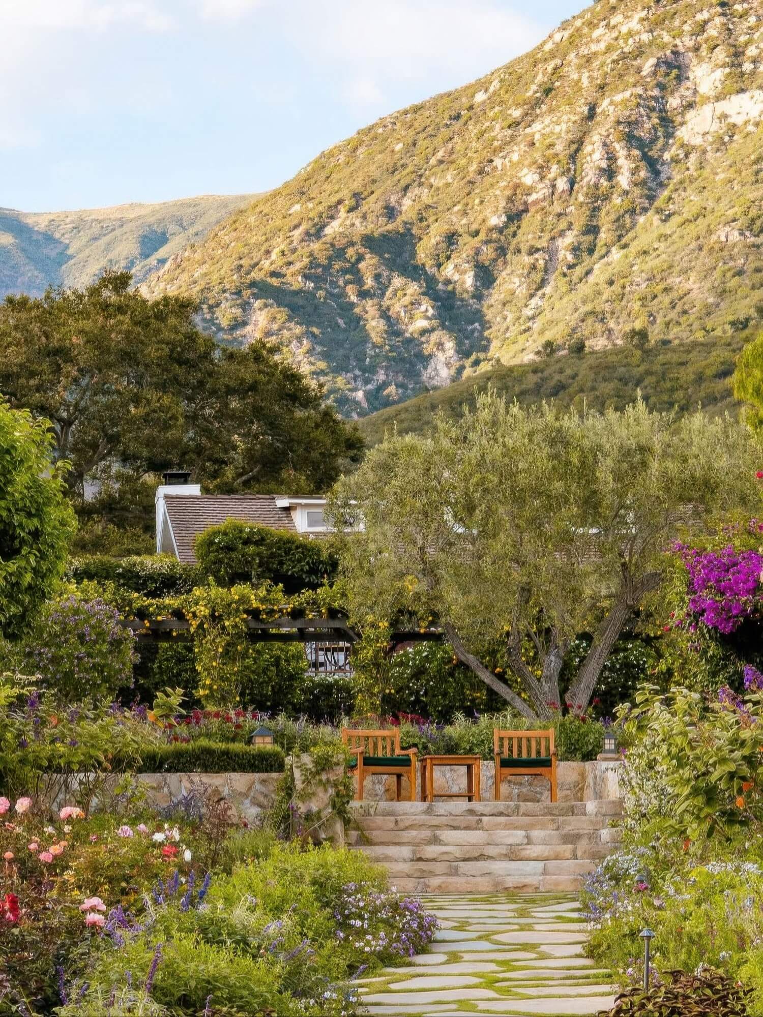 Stone garden path climbing through lush flowering cottage gardens below the mountains at San Ysidro Ranch, Montecito