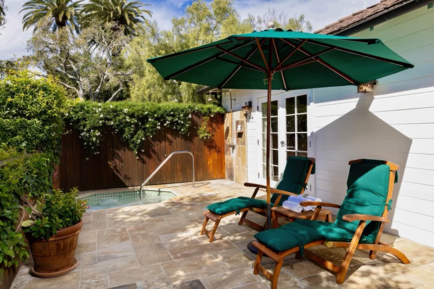 Private cottage patio with teak loungers, a green umbrella and a plunge pool at San Ysidro Ranch, Montecito