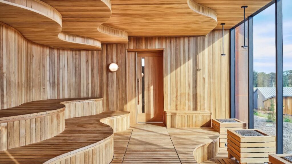 Curved cedar sauna with tiered benches and floor-to-ceiling window at the Halehouse spa, Stanly Ranch, Auberge Resorts Collection, Napa