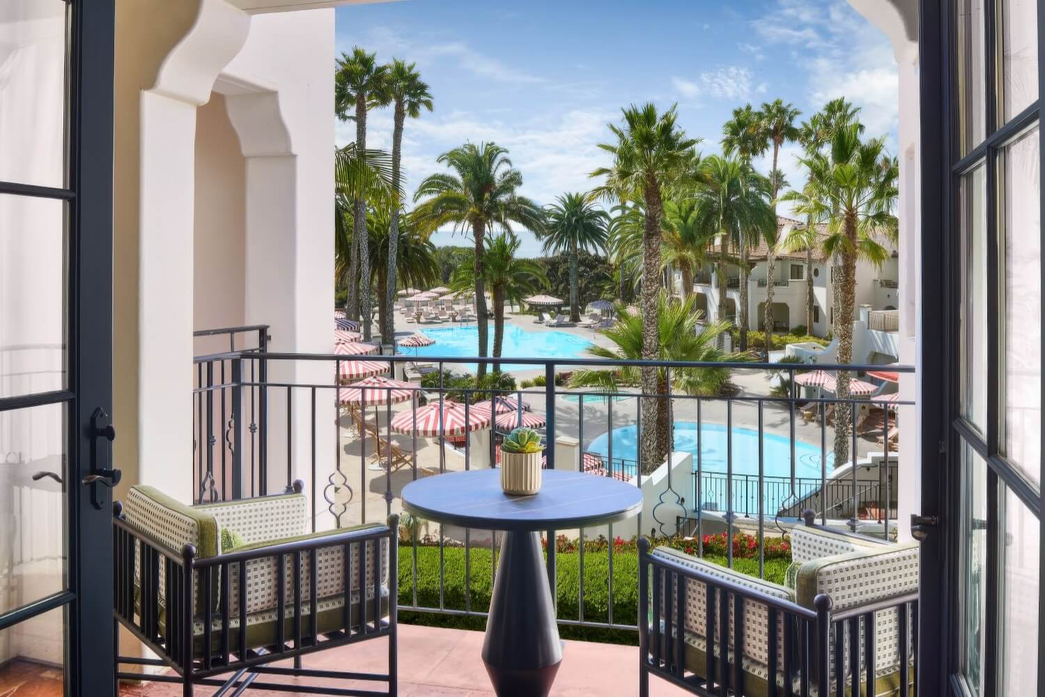 Guest balcony with bistro seating overlooking the palm-lined pools at The Ritz-Carlton Bacara, Santa Barbara