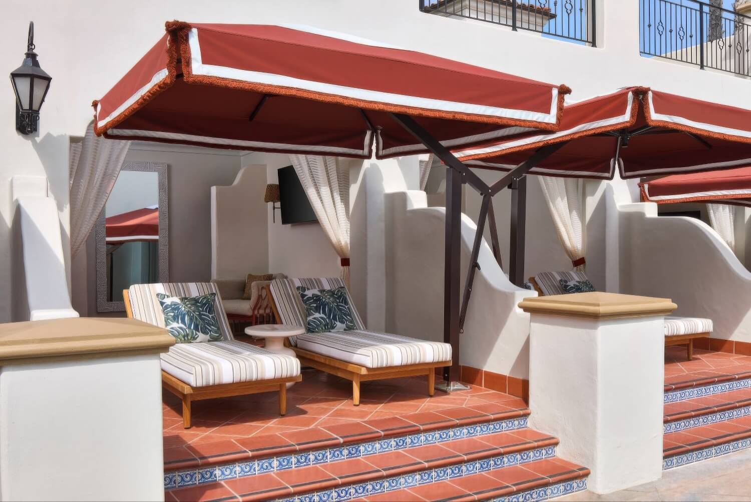 Poolside cabana with red fringed awnings and striped daybeds on tiled steps at The Ritz-Carlton Bacara, Santa Barbara