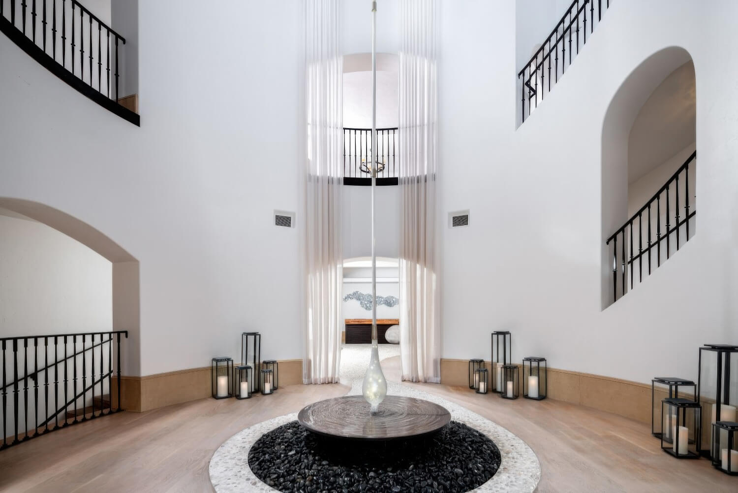 Double-height spa atrium with a black-pebble water feature and lantern-lit staircases at The Ritz-Carlton Bacara, Santa Barbara