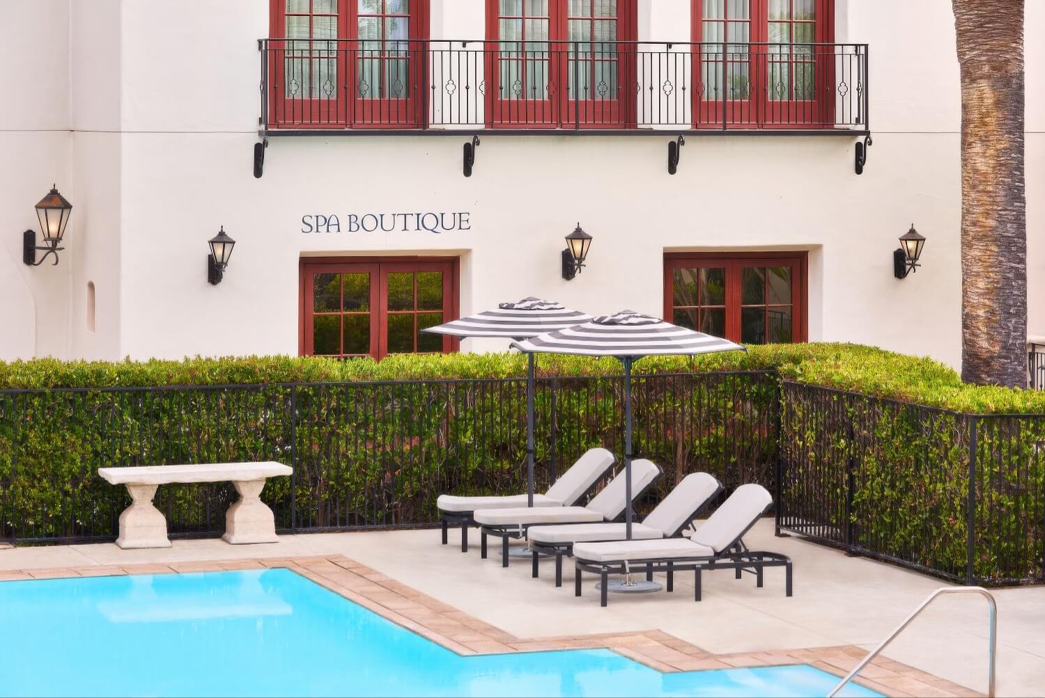 Spa Boutique façade with striped umbrellas and loungers beside the pool at The Ritz-Carlton Bacara, Santa Barbara