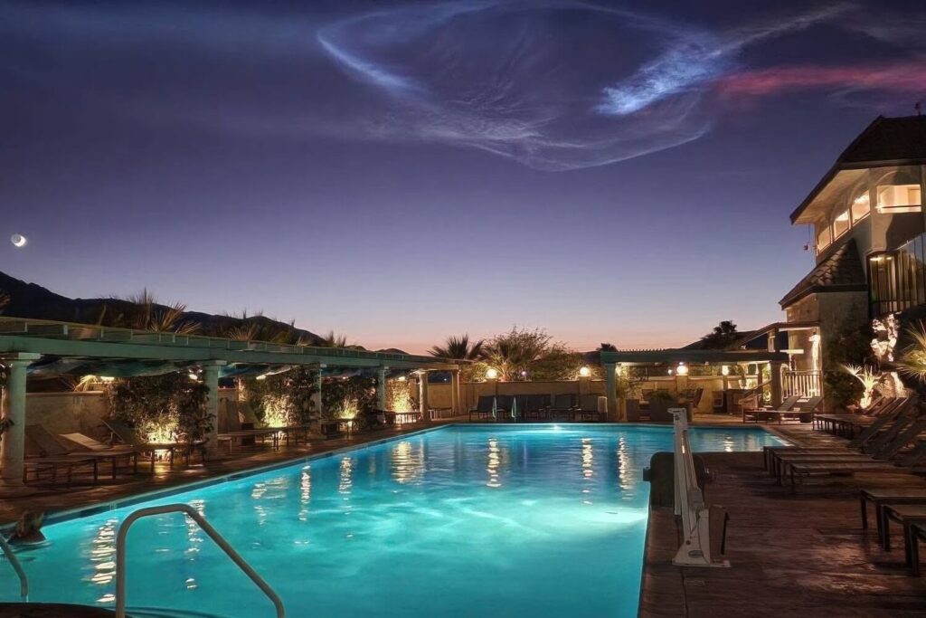 Illuminated mineral pool and pergola cabanas under a twilight sky in Desert Hot Springs, California