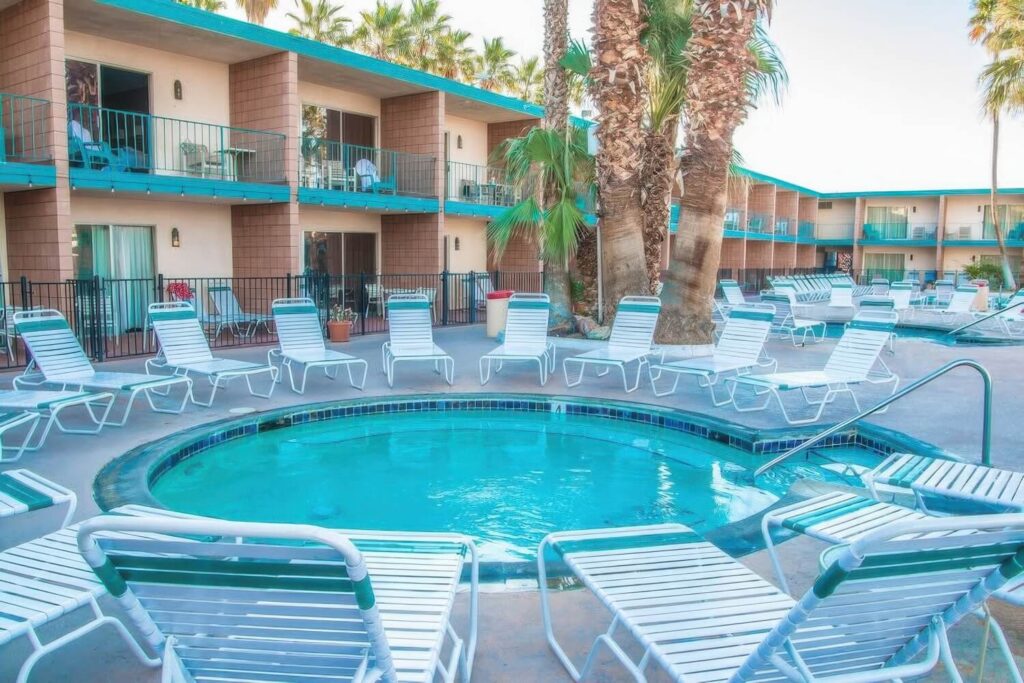 Round mineral hot pool ringed by loungers at the retro two-storey Desert Hot Springs Spa Hotel, California