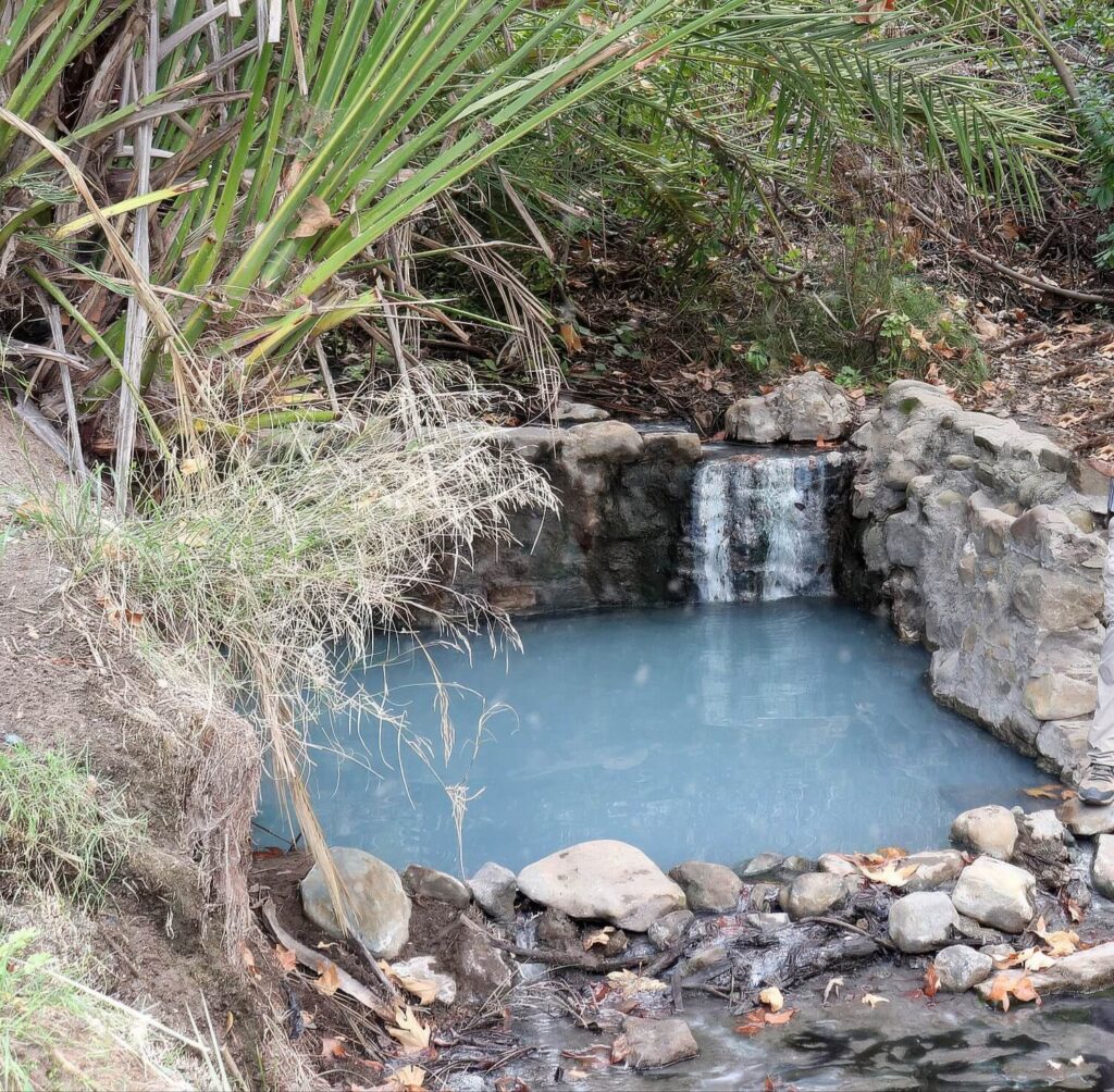 Milky turquoise spring water cascading into a rock-rimmed soaking pool at Gaviota Hot Springs, Santa Barbara County, California