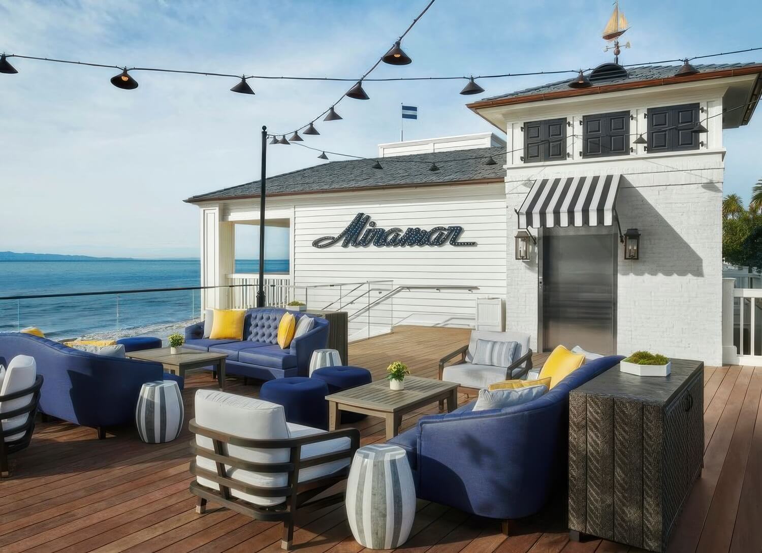 Beachfront suite deck with blue sofas and a fire table directly above the sand at Rosewood Miramar Beach, Montecito