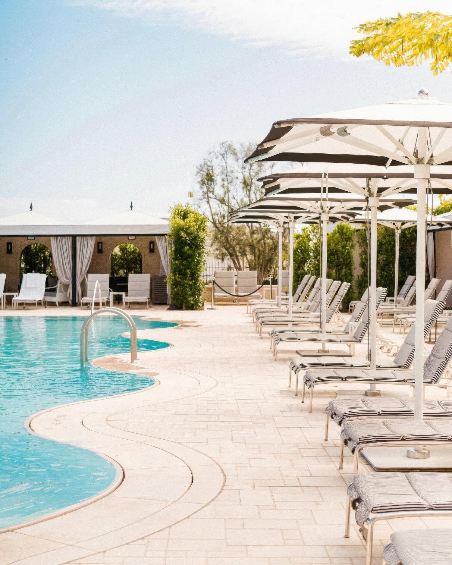 Curtained cabanas and umbrella-shaded loungers curving around the pool at Rosewood Miramar Beach, Montecito