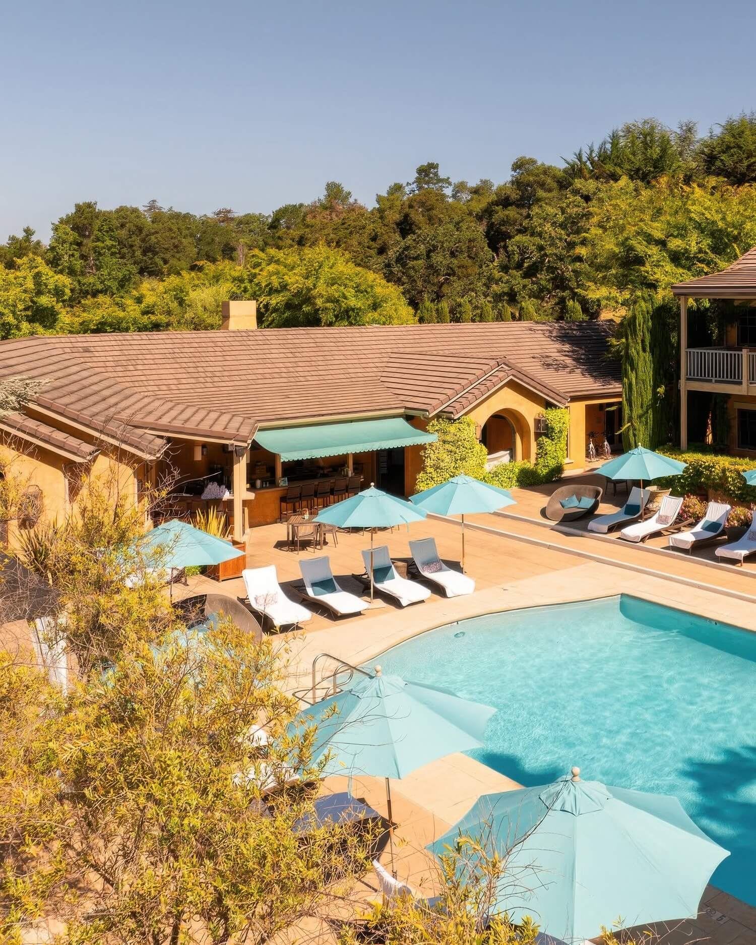 Pool deck with teal umbrellas, white loungers and the poolside bar at Bernardus Lodge and Spa, Carmel Valley