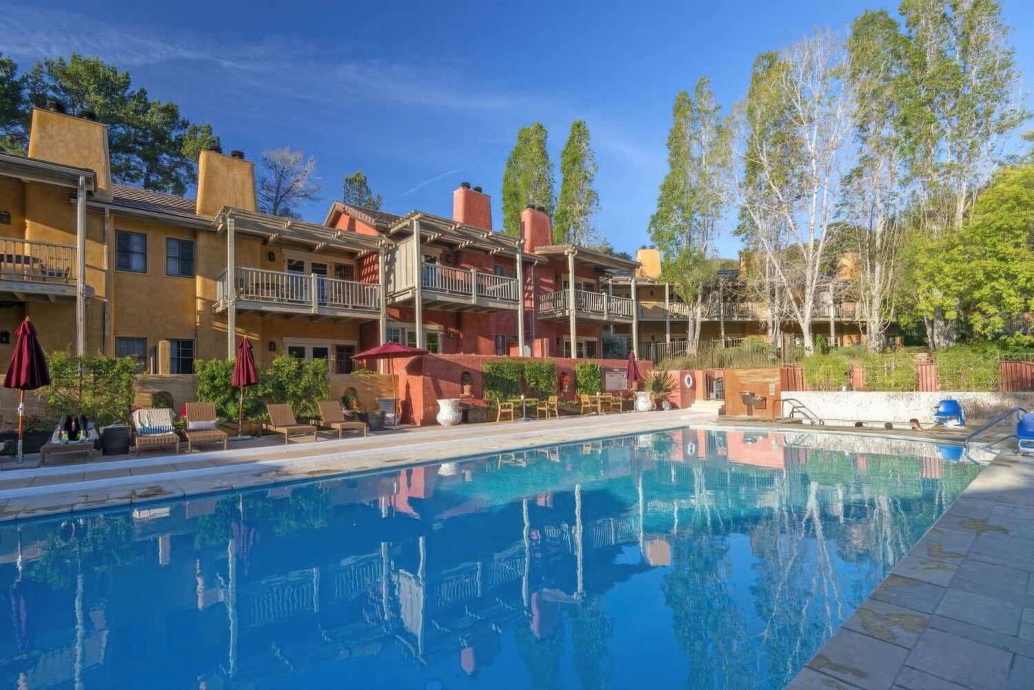 Outdoor pool reflecting the ochre lodge balconies and poplar trees at Bernardus Lodge and Spa, Carmel Valley