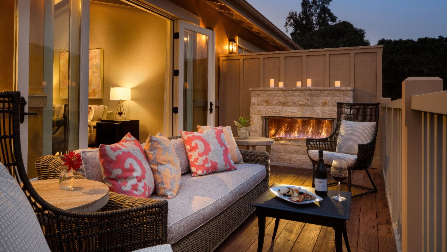Private balcony with wicker sofa, outdoor fireplace and wine at twilight at Bernardus Lodge and Spa, Carmel Valley