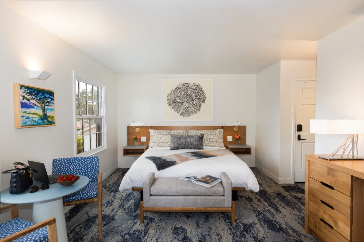 Guest room with wood plank headboard, floating nightstands and cafe table for two at Carmel Beach Hotel, Carmel-by-the-Sea