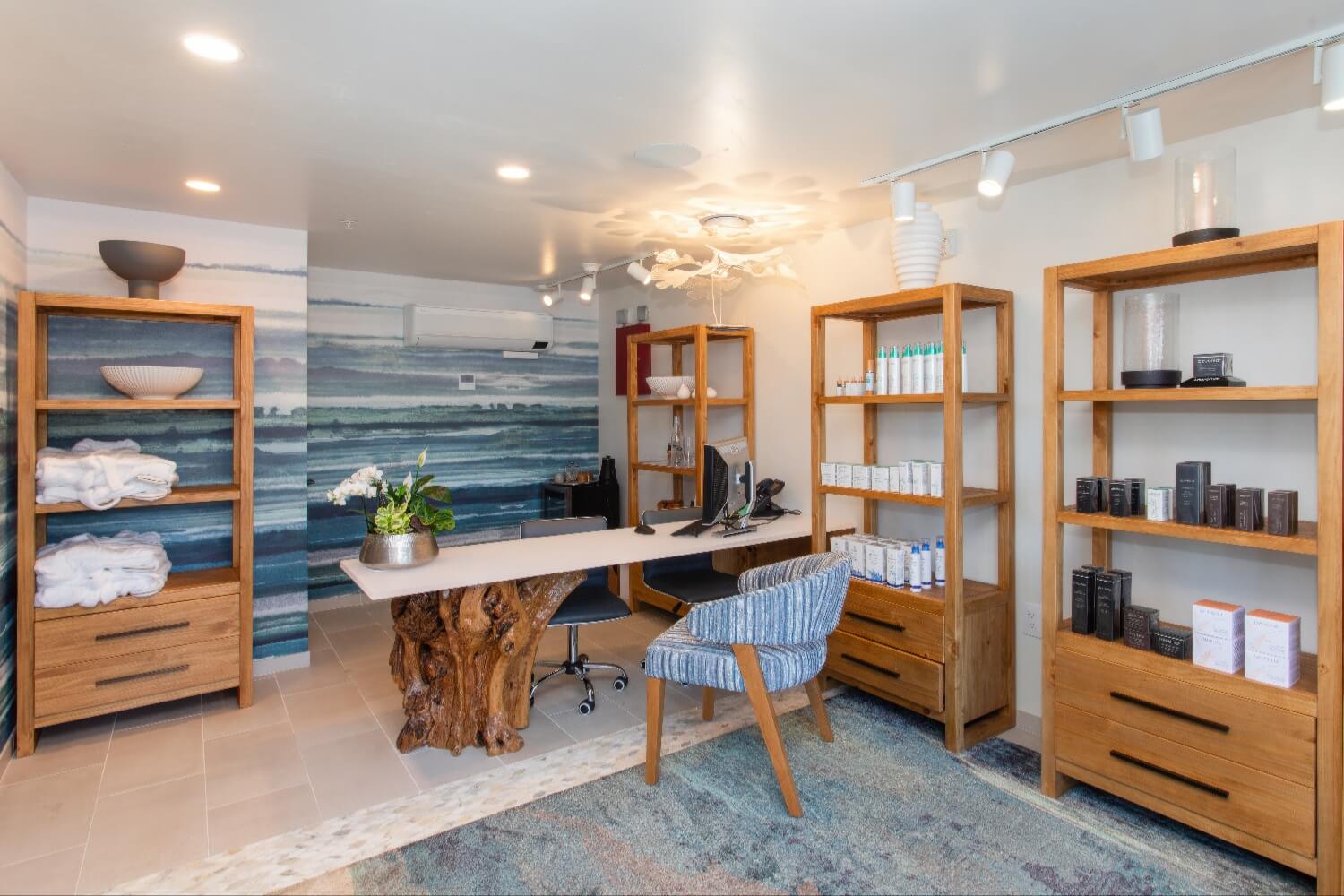 Spa Adeline reception with skincare shelves, folded robes and watercolor ocean mural at Carmel Beach Hotel, Carmel-by-the-Sea