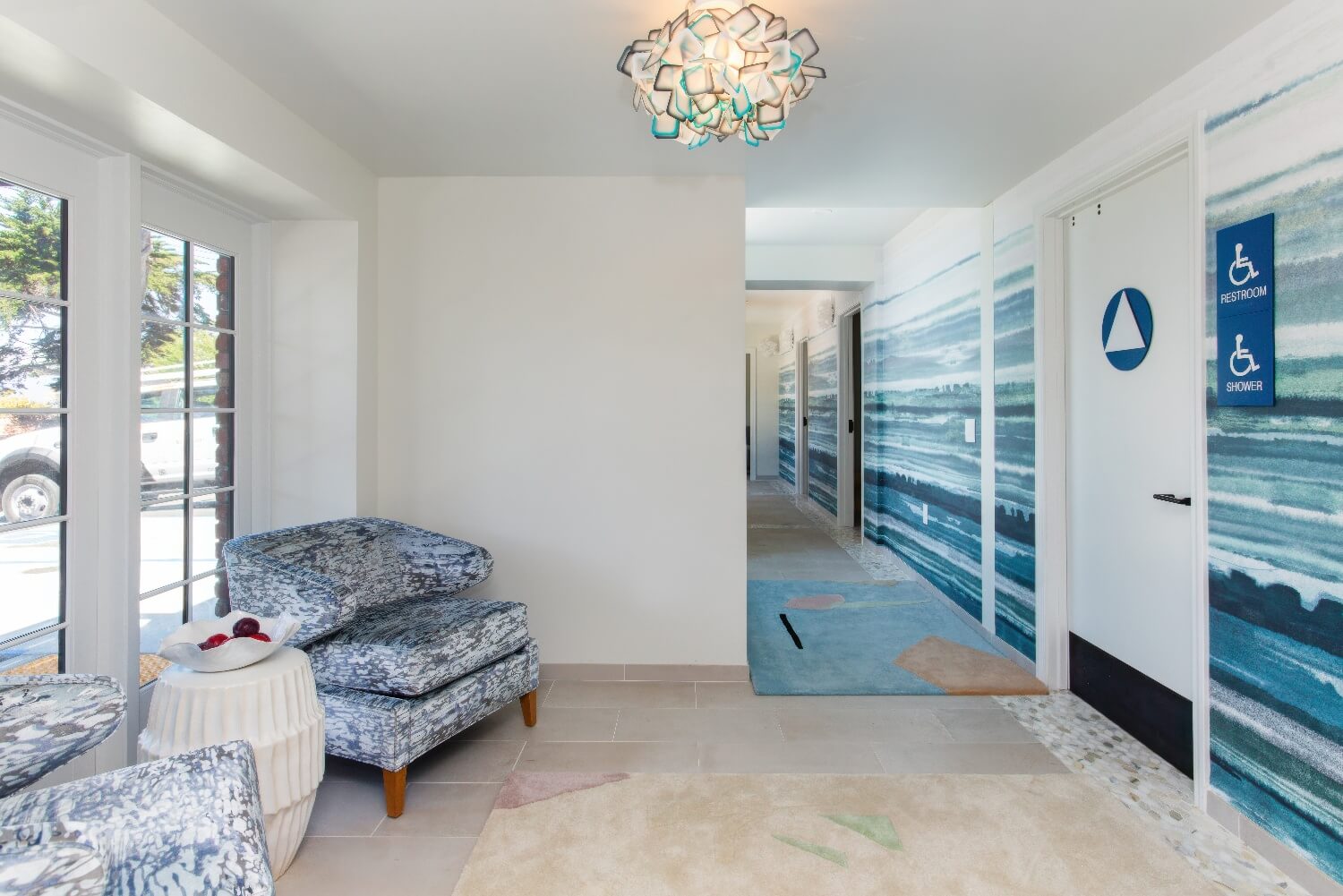 Spa Adeline waiting area with watercolor wave walls and accessible shower signage at Carmel Beach Hotel, Carmel-by-the-Sea